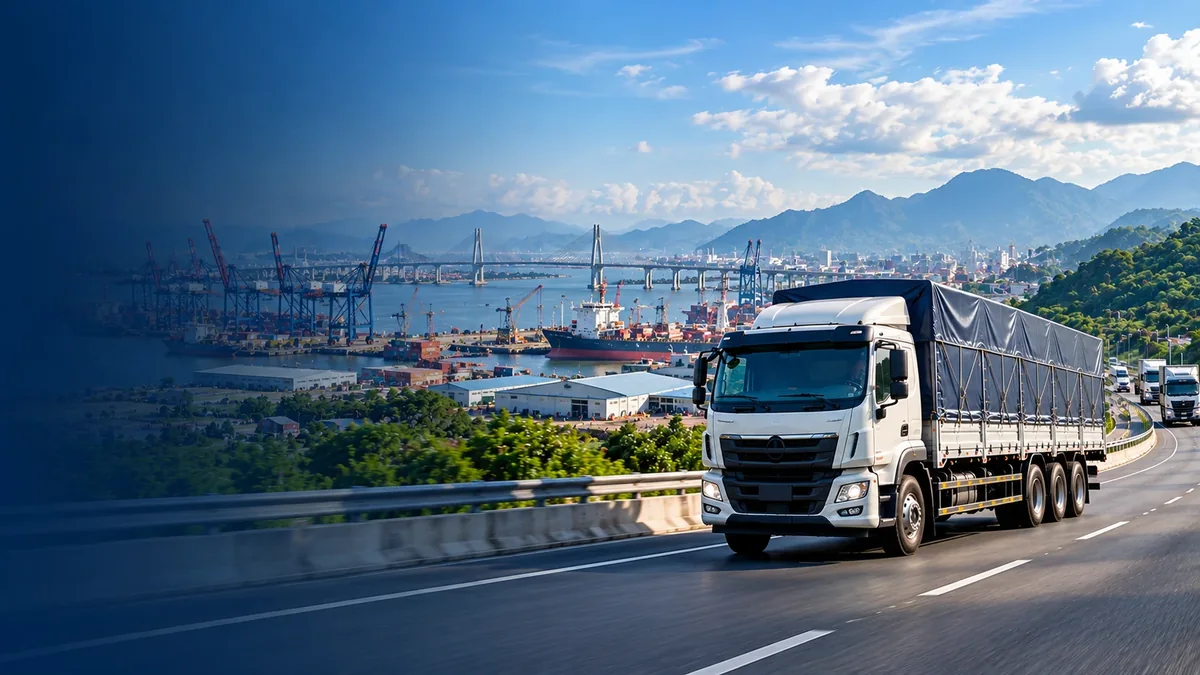 Xe tải thùng bạt chạy trên đường với nền khu cảng biển phía sau, minh họa tuyến Hà Tĩnh đi Hải Phòng